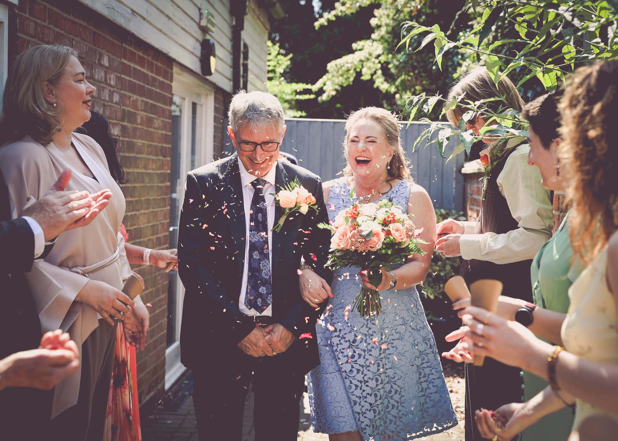 A bride and groom walking through an aisle of confetti outside woodbridge registry office on a wedding day in Woodbridge captured by Suffolk Wedding Photographer Hayley Denston Photography